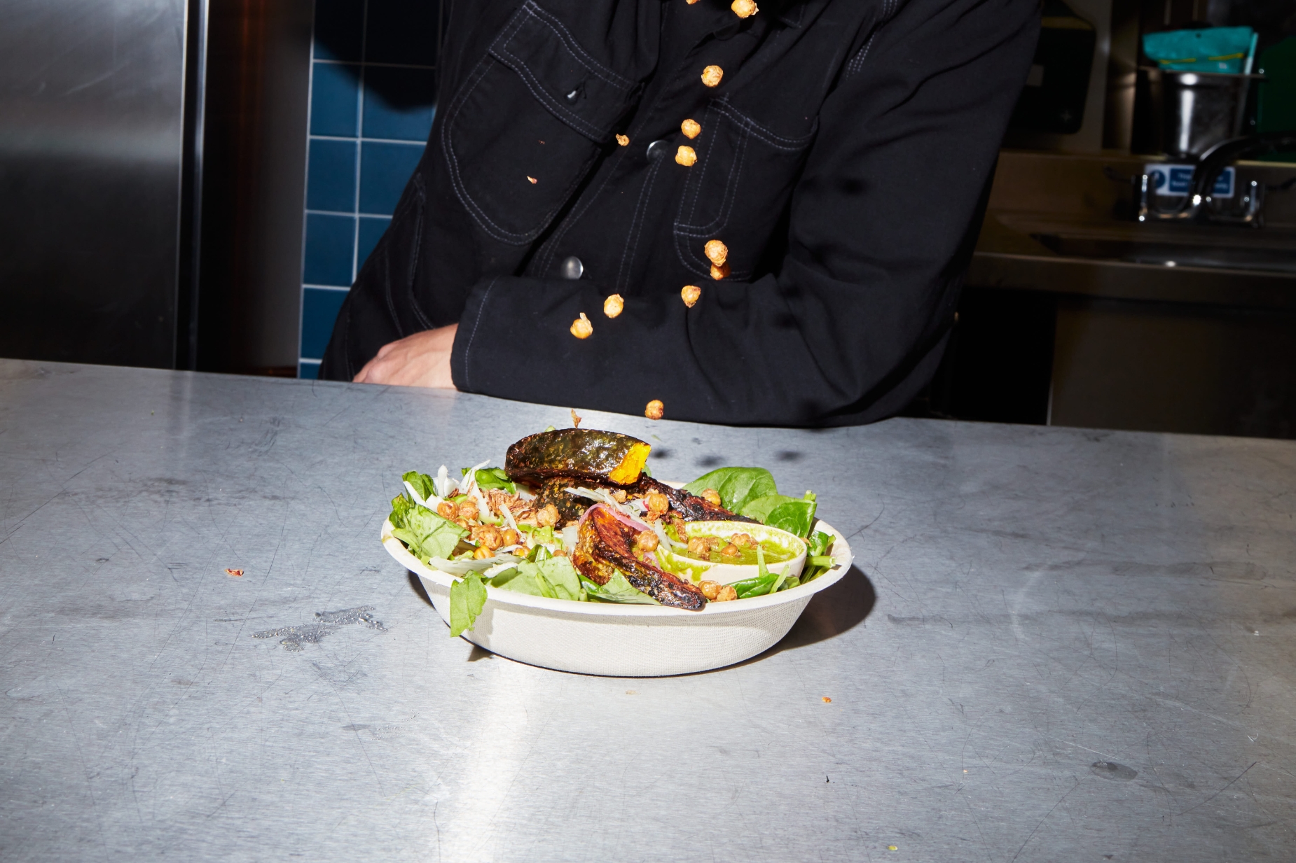 Chef, Jesse Jenkins, sprinkles crispy chickpeas on ADIP x atis bowl